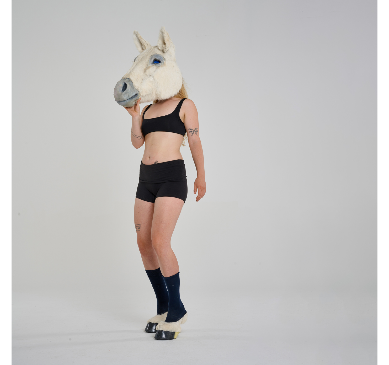 The artist wearing the horse mask and hoofed shoes