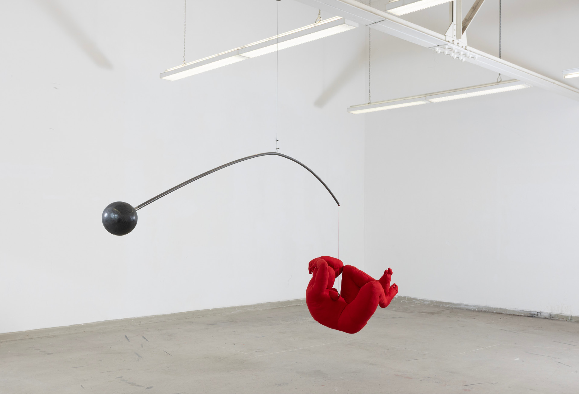 Room view: the red figure hanging from the steel arm in a white gallery